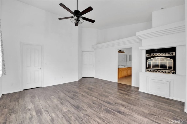 unfurnished living room with wood finished floors, high vaulted ceiling, ceiling fan, and baseboards