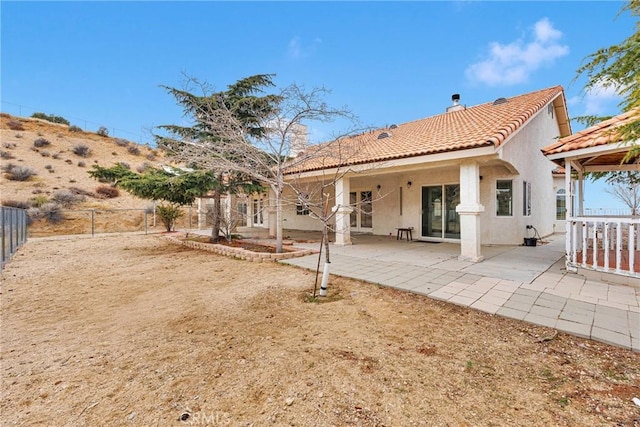 rear view of property with a patio area, stucco siding, a tile roof, and fence