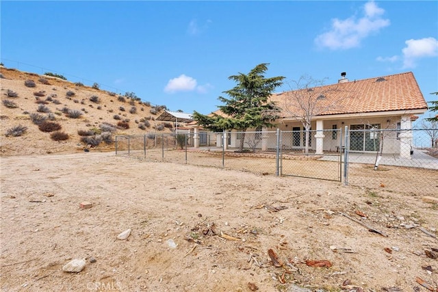 back of property with a tiled roof, fence, a gate, and a chimney