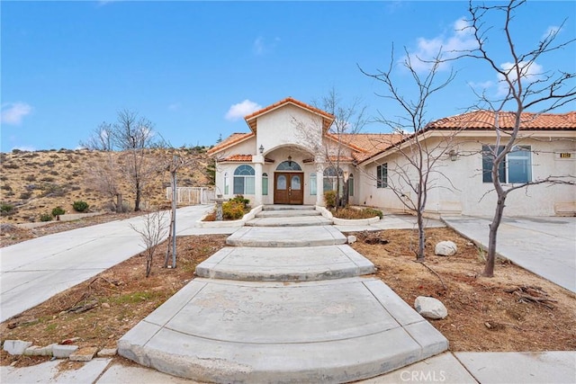 mediterranean / spanish home with french doors, stucco siding, and a tiled roof