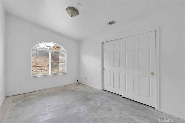 unfurnished bedroom featuring concrete floors, a closet, baseboards, and visible vents