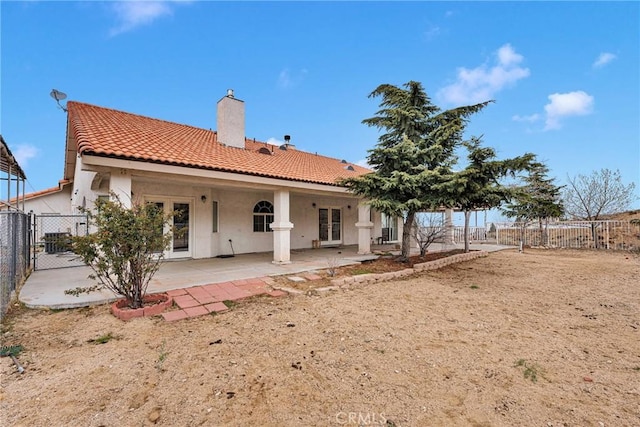 back of house featuring a patio, fence, a chimney, stucco siding, and french doors