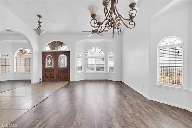 foyer entrance featuring plenty of natural light, a towering ceiling, baseboards, and wood finished floors