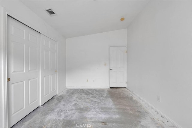 unfurnished bedroom featuring lofted ceiling, visible vents, concrete flooring, a closet, and baseboards