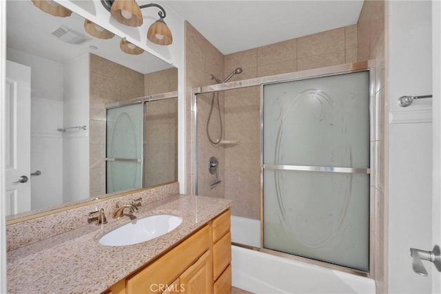 bathroom with vanity, visible vents, and combined bath / shower with glass door