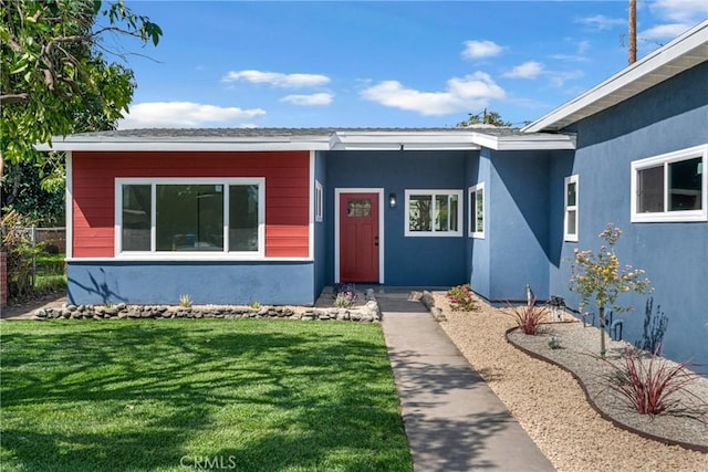 doorway to property featuring stucco siding and a yard