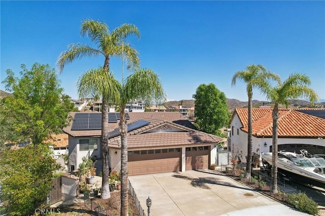 22176 Dogie Pl, Canyon Lake, CA 92587 - view of front facade featuring concrete driveway, roof mounted solar panels, a garage, a tiled roof, and stucco siding