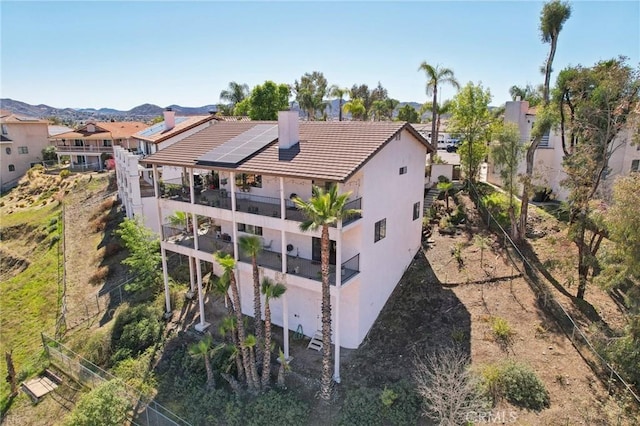 22176 Dogie Pl, Canyon Lake, CA 92587 - back of house featuring a balcony, stucco siding, a chimney, solar panels, and a tile roof
