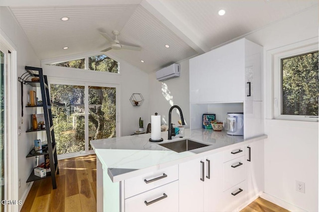 kitchen featuring a sink, a peninsula, wood finished floors, and vaulted ceiling