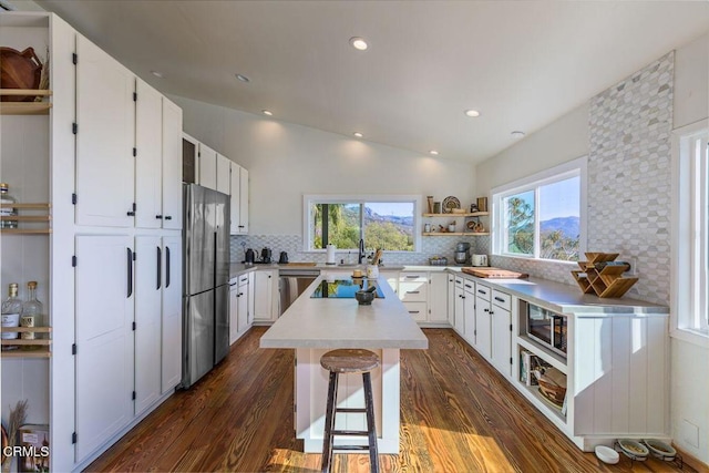 kitchen featuring open shelves, lofted ceiling, appliances with stainless steel finishes, and dark wood finished floors