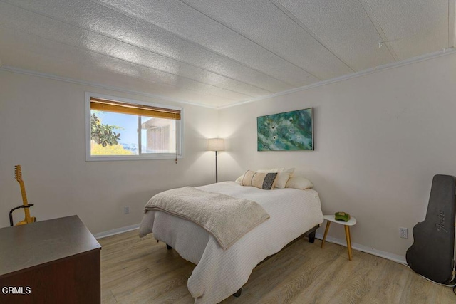 bedroom with crown molding, wood finished floors, baseboards, and a textured ceiling