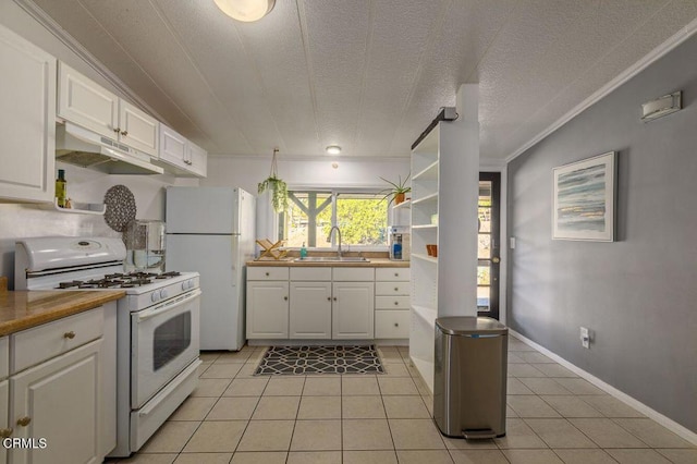 kitchen with under cabinet range hood, white appliances, white cabinetry, and a sink