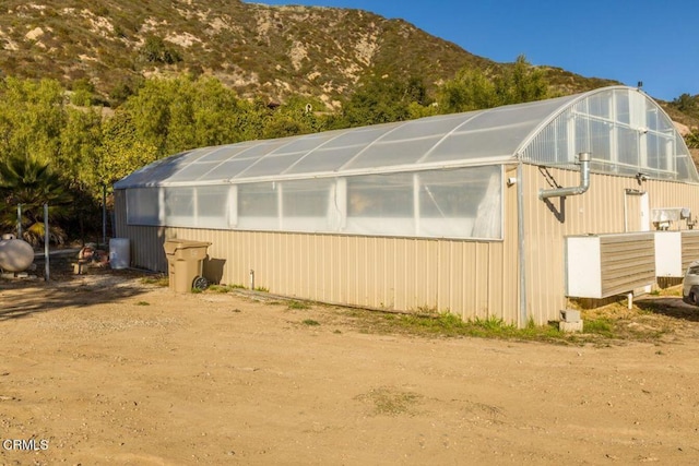 view of property exterior with an exterior structure, a mountain view, and an outbuilding