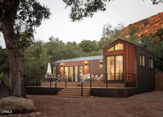 back of property featuring metal roof and a deck