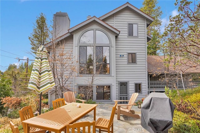 rear view of property featuring a patio area and a chimney