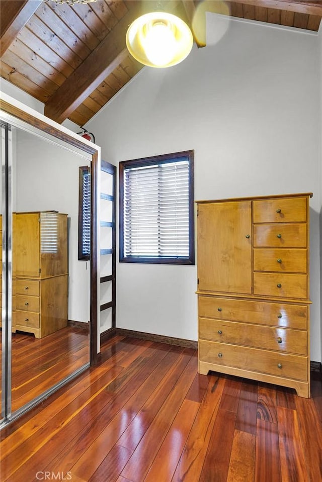 unfurnished bedroom featuring lofted ceiling with beams, a closet, and dark wood-type flooring