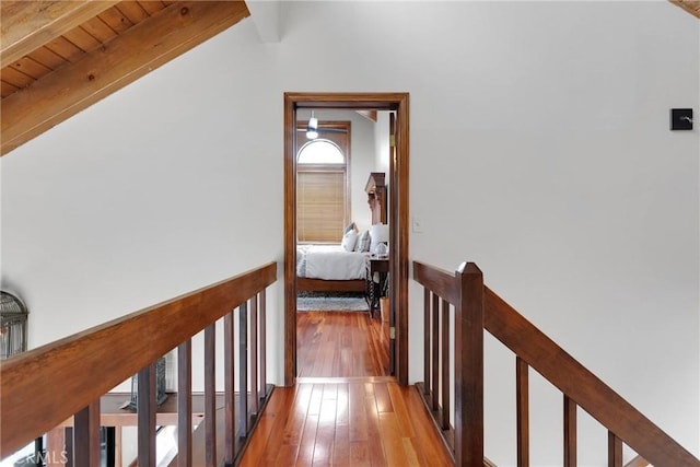 corridor featuring lofted ceiling with beams, an upstairs landing, wood-type flooring, and wooden ceiling