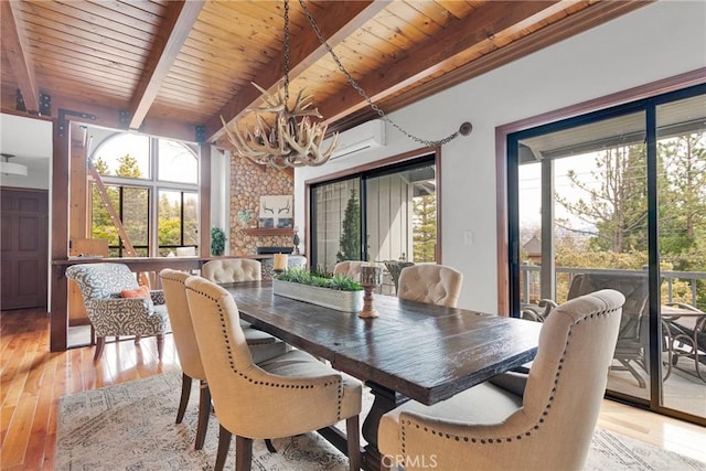 dining room featuring beamed ceiling, light wood-style floors, a healthy amount of sunlight, and a notable chandelier