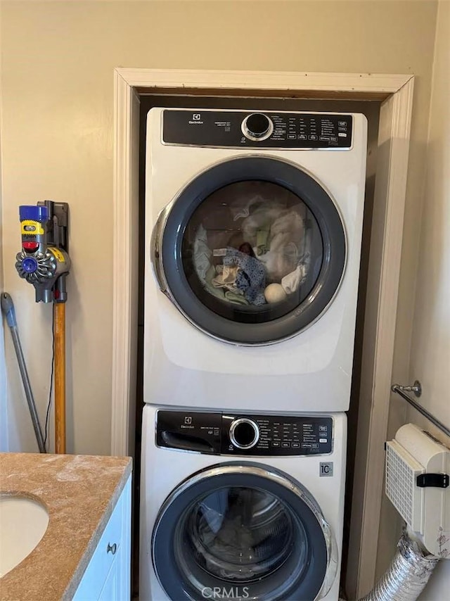 laundry room featuring stacked washer / drying machine and a sink