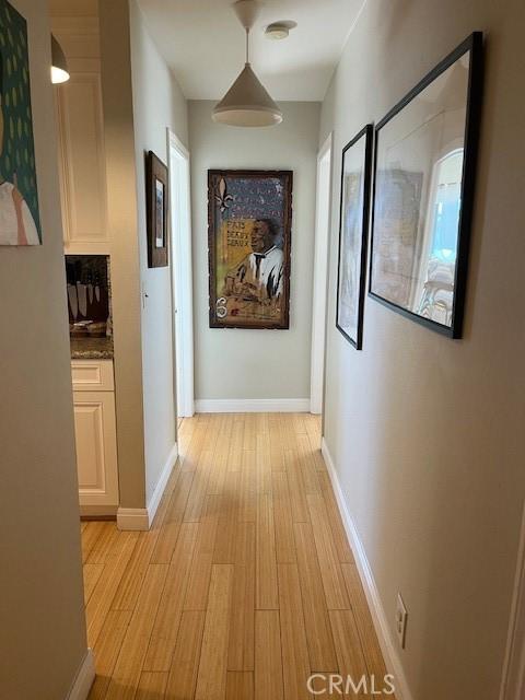 hallway with light wood-type flooring and baseboards