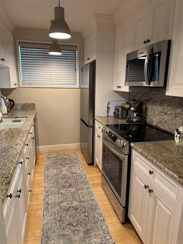 kitchen featuring a sink, backsplash, white cabinetry, appliances with stainless steel finishes, and light wood finished floors