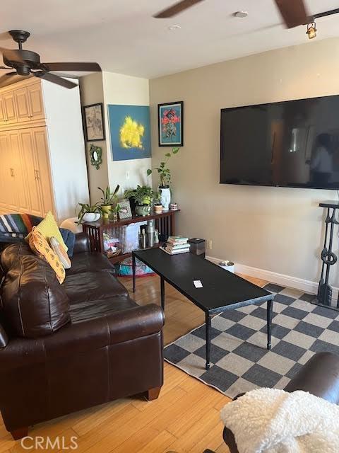 living room with a ceiling fan, light wood-style floors, and baseboards