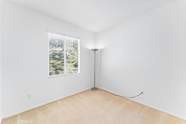 unfurnished room featuring light colored carpet and baseboards