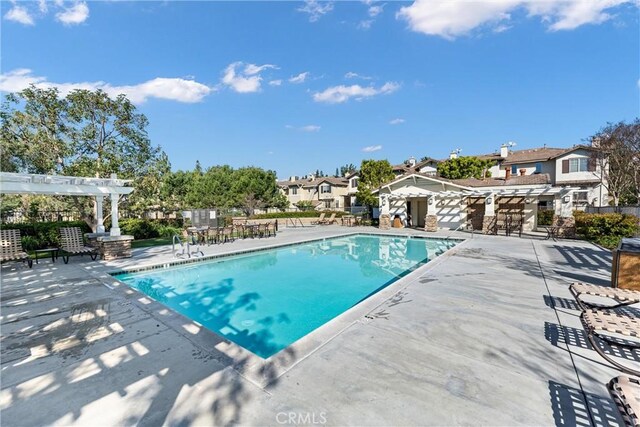 community pool with a pergola, a patio, and fence