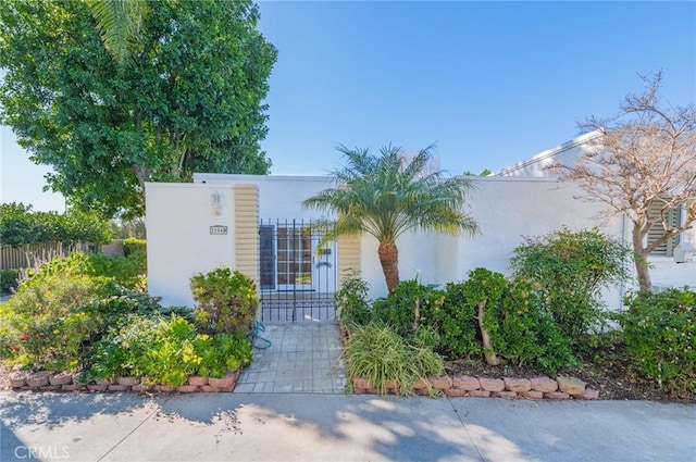 view of front of property featuring stucco siding, fence, and a gate