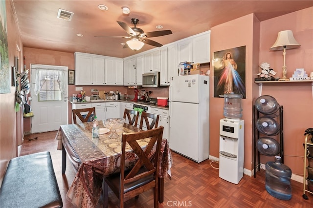 kitchen featuring stainless steel microwave, white cabinetry, visible vents, and freestanding refrigerator