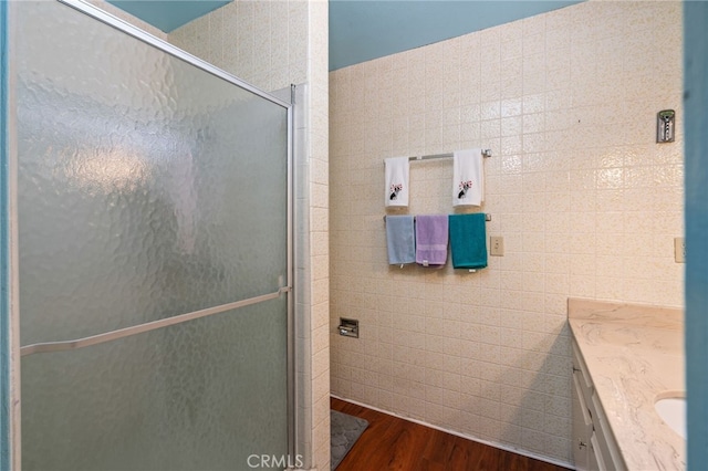 bathroom with vanity, tile walls, wood finished floors, and a stall shower