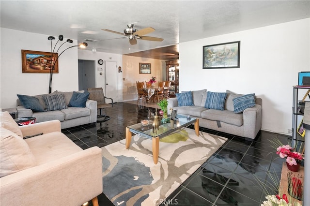 living area with dark tile patterned flooring, a ceiling fan, and visible vents