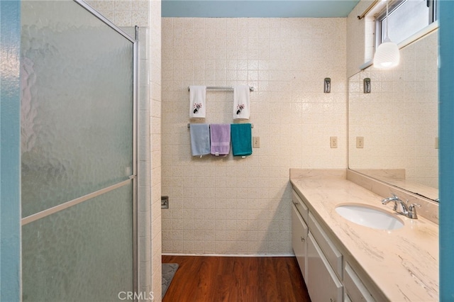 bathroom featuring vanity, tile walls, wood finished floors, and a stall shower