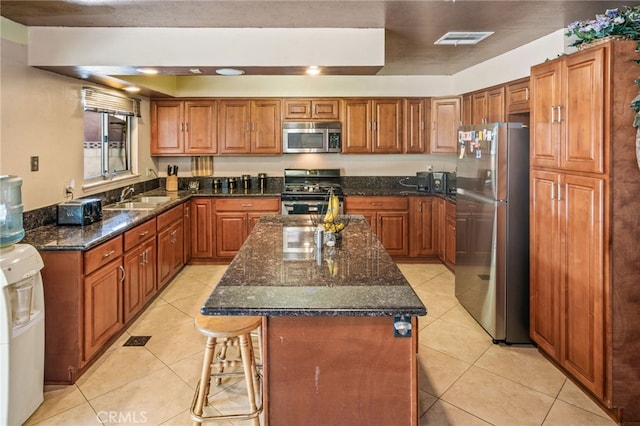 kitchen featuring visible vents, light tile patterned floors, brown cabinets, stainless steel appliances, and a sink