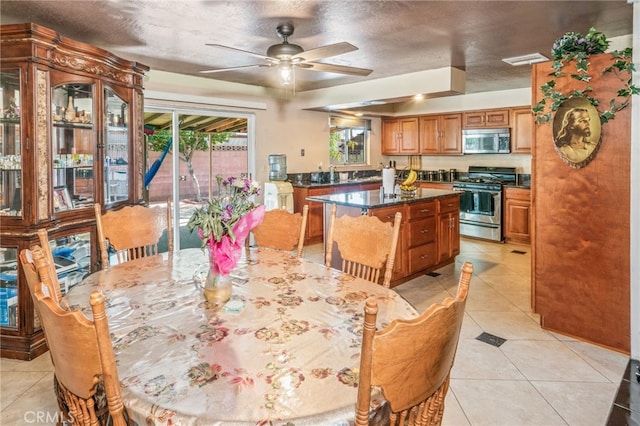 kitchen with visible vents, brown cabinets, a kitchen island, appliances with stainless steel finishes, and light tile patterned floors