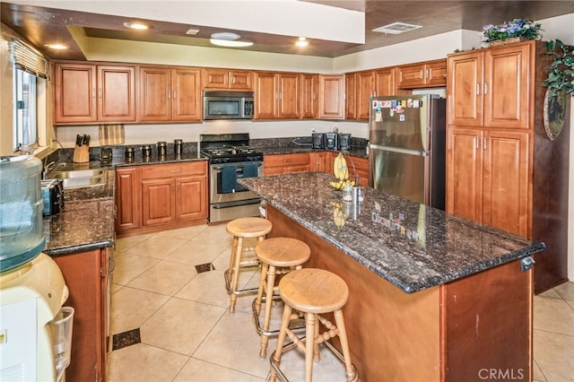 kitchen with visible vents, brown cabinets, a sink, stainless steel appliances, and light tile patterned floors