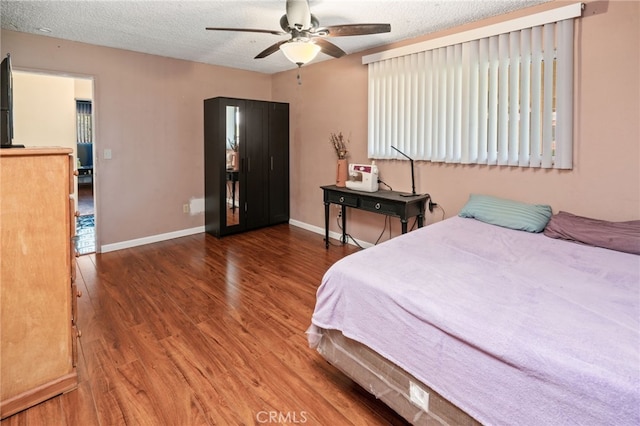 bedroom with baseboards, a textured ceiling, wood finished floors, and a ceiling fan