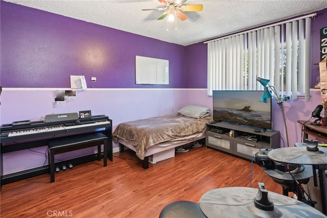 bedroom with a textured ceiling, wood finished floors, and a ceiling fan