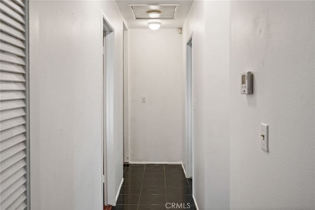 hall with attic access and dark tile patterned floors