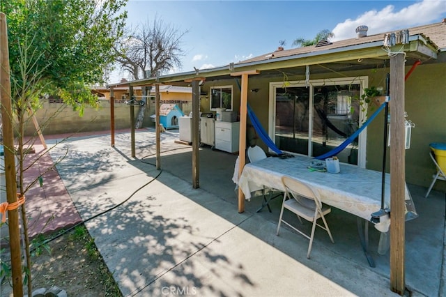 view of patio with outdoor dining area, washing machine and dryer, and fence