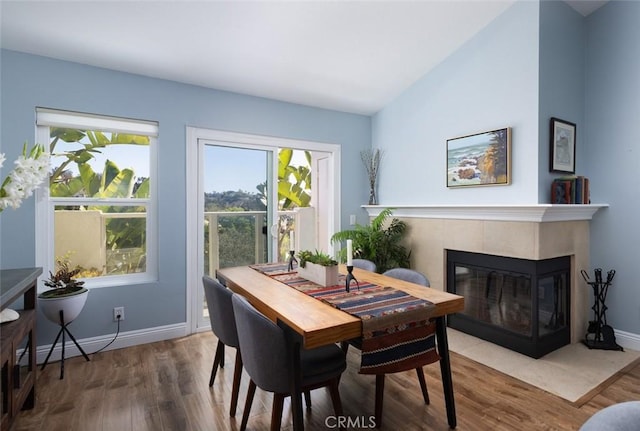 dining area with baseboards, wood finished floors, and a fireplace