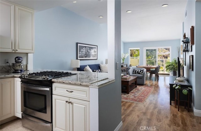 kitchen featuring stainless steel gas stove, light wood-style flooring, light stone counters, open floor plan, and recessed lighting