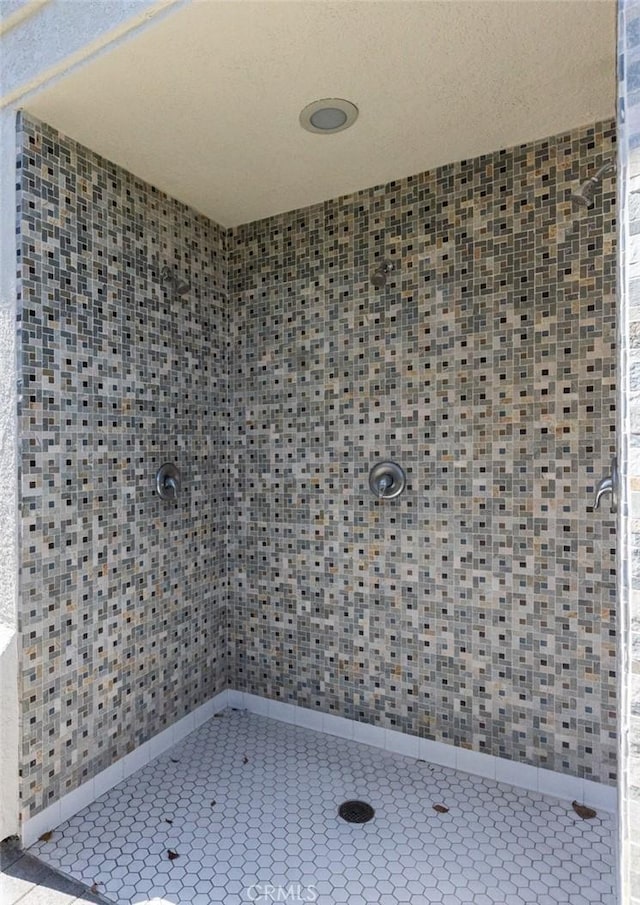 bathroom featuring tile patterned flooring and tiled shower