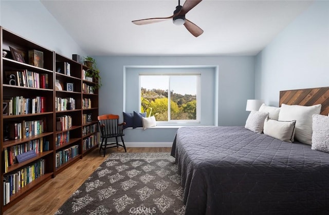 bedroom with vaulted ceiling, wood finished floors, and baseboards