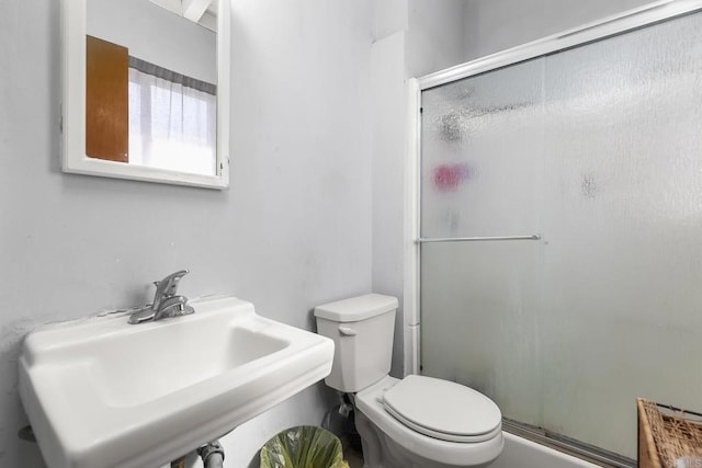 bathroom featuring a shower stall, toilet, and a sink