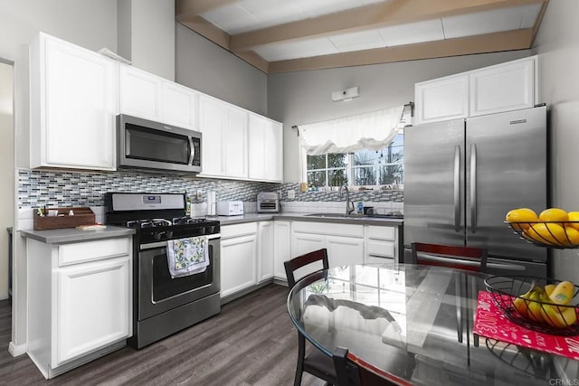 kitchen featuring a sink, tasteful backsplash, dark wood-style floors, white cabinetry, and appliances with stainless steel finishes