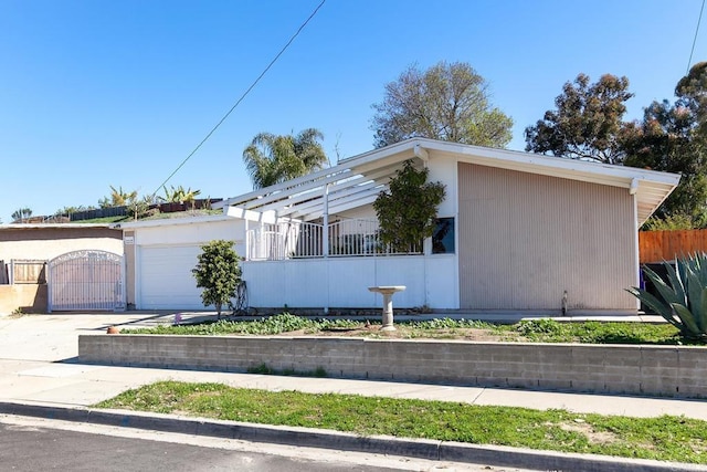 view of home's exterior with fence, concrete driveway, an attached garage, and a gate