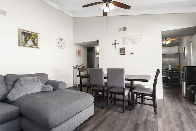 dining space featuring ceiling fan, visible vents, dark wood finished floors, and vaulted ceiling with beams