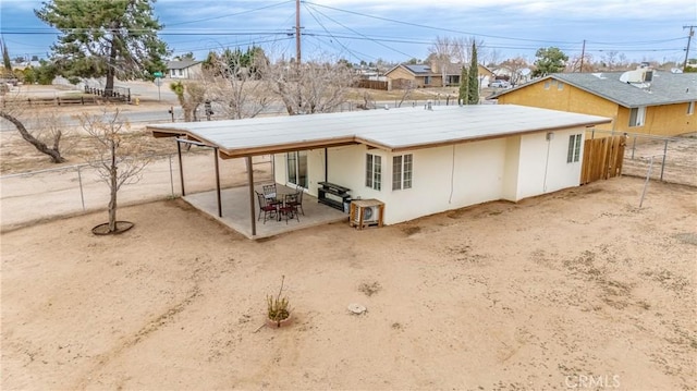 back of house with stucco siding, a patio, a fenced backyard, and dirt driveway