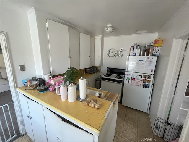 kitchen featuring light tile patterned floors, white appliances, white cabinetry, and tile counters